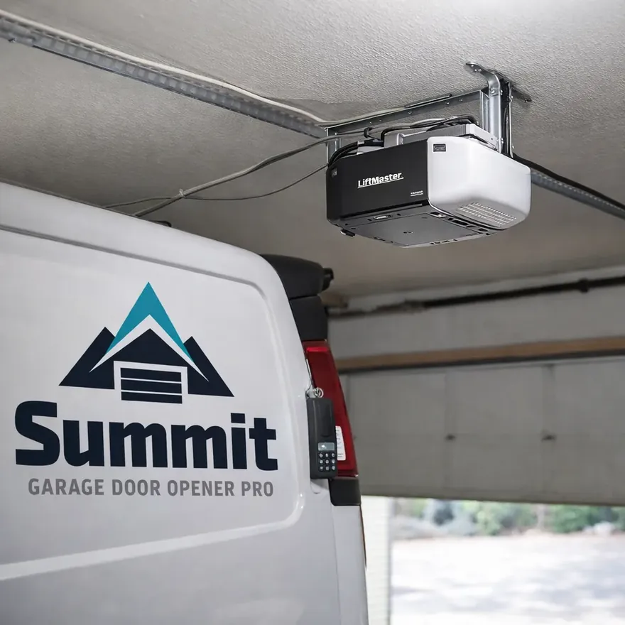 A newly repaired garage door opener mounted on the ceiling track of a home garage, with tidy wiring and a labeled remote.